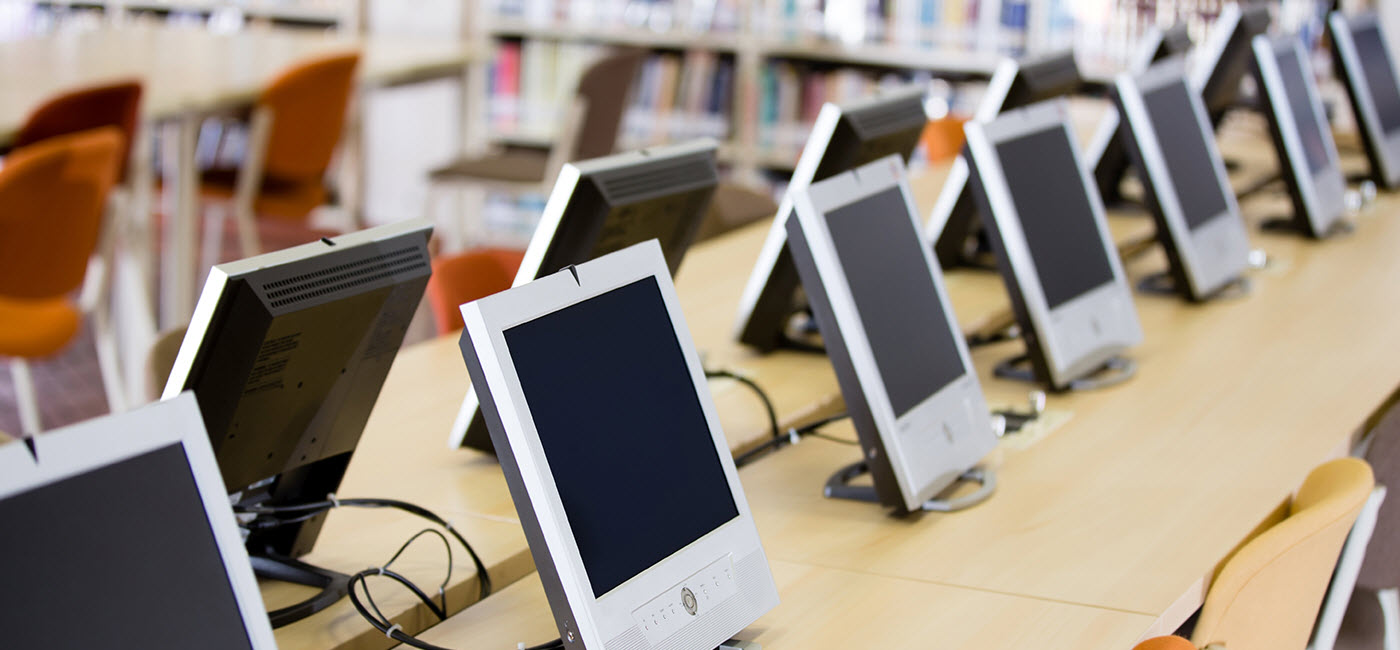 Row of computer monitors on a long desk in the library.